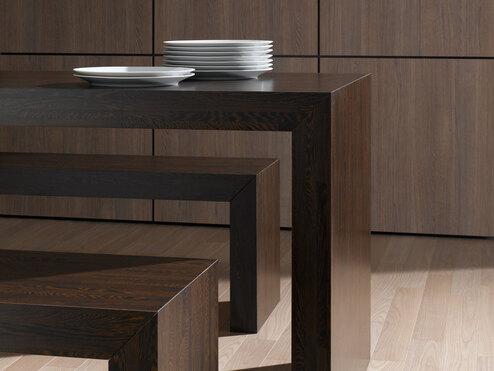 Detailaufnahme einer Esstischgruppe aus dunklem Massivholz Detailaufnahme eines Esszimmers aus dunklem Massivholz mit Sitzbänken und Einbauschrank im Hintergrund